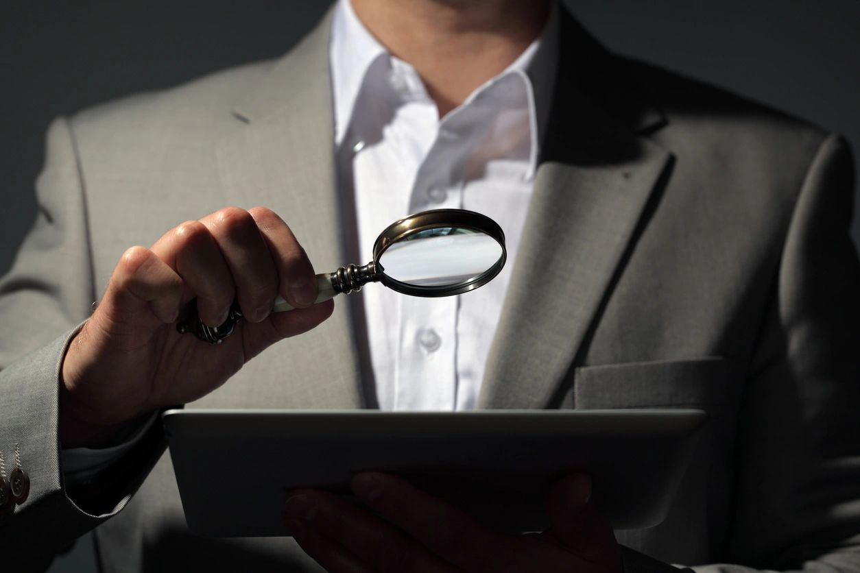 Investigator with magnifying glass reviewing evidence